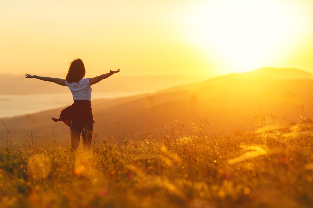 a woman standing in front of a sunset.